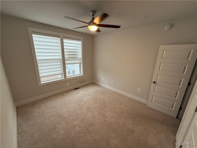 Carpeted empty room with ceiling fan, baseboards,