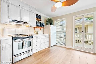 Kitchen featuring ceiling fan, ornamental molding, white cabinetry, stainless steel range with electric cooktop, and white fridge