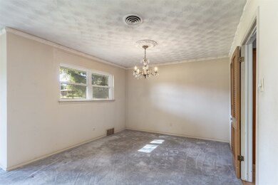 Carpeted empty room with a chandelier, ornamental molding, and a textured ceiling