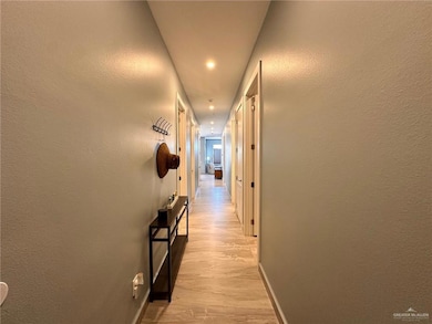 Corridor with light wood-style flooring, a textured wall, and recessed lighting