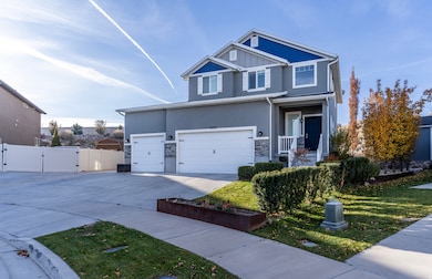 View of front facade with a gate, driveway, stone siding, stucco siding, and a garage