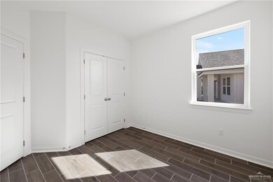 Unfurnished bedroom with wood finish floors, a closet, and baseboards
