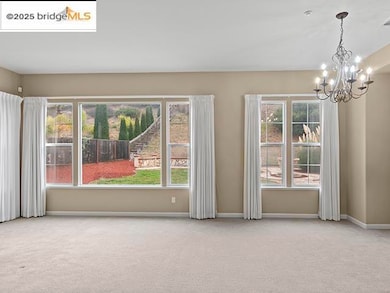 Carpeted empty room featuring a chandelier and baseboards