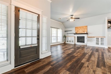 Unfurnished living room featuring vaulted ceiling, a ceiling fan, a large fireplace, wood finished floors, and baseboards