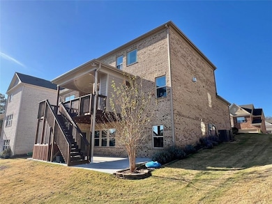 Rear view of house featuring a patio, brick siding, and a lawn