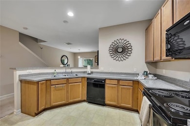 Kitchen featuring black appliances, a peninsula, and brown cabinetry