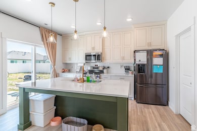 Kitchen featuring stainless steel appliances, light wood-style flooring, light countertops, decorative backsplash, and recessed lighting