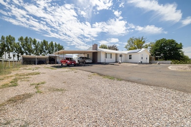 View of front of home featuring a chimney, solar panels, driveway, and a carport