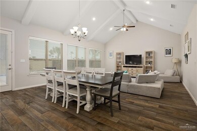 Dining space with ceiling fan with notable chandelier, high vaulted ceiling, and beamed ceiling