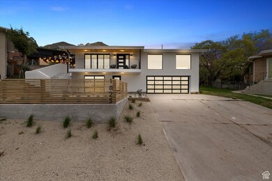 View of front of property featuring fence, a balcony, stucco siding, an attached garage, and driveway