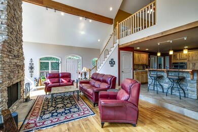 View of the great room that opens to the kitchen and wrap around deck. Soaring two story wood burning fireplace. 