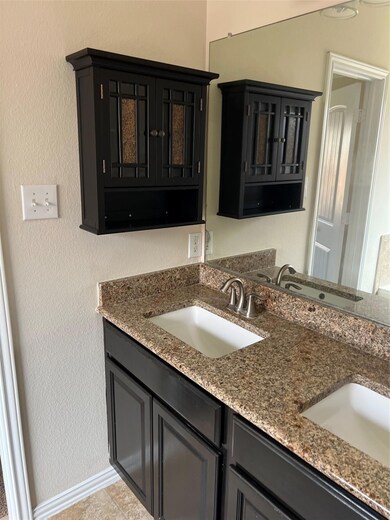 Kitchen with dark cabinetry, light stone counters