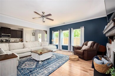 Living area with a ceiling fan, light wood-style floors, crown molding, and a fireplace