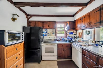 Kitchen featuring white appliances, beam ceiling, and light countertops