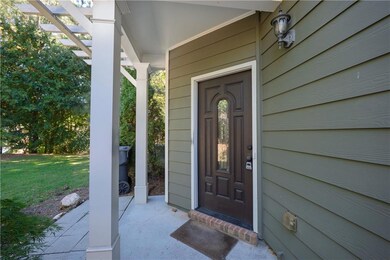 Property entrance with a lawn, covered porch, and a pergola