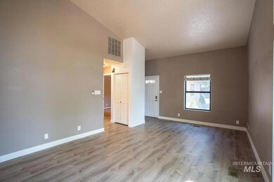 Spare room featuring wood finished floors, a textured ceiling, and high vaulted ceiling