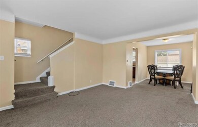 Carpeted living area featuring stairway and baseboards