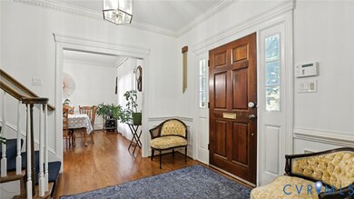Foyer entrance featuring ornamental molding, wood finished floors, and stairs
