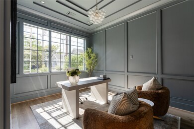 Another angle of the office space. The custom, paneled trim adds dimension and elegance to the room and the hand-blown bubble chandelier adds a touch of whimsy. These walls are great for a TV or artwork.