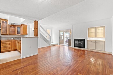 Unfurnished living room featuring light wood finished floors, a textured ceiling, stairway, and a glass covered fireplace