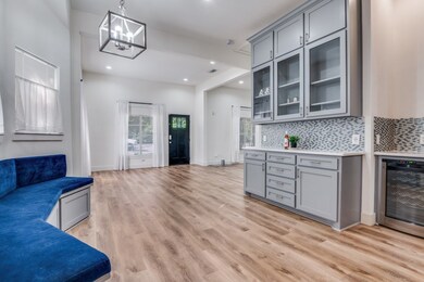 Kitchen with gray cabinets, hanging light fixtures, beverage cooler, glass insert cabinets, and plenty of natural light
