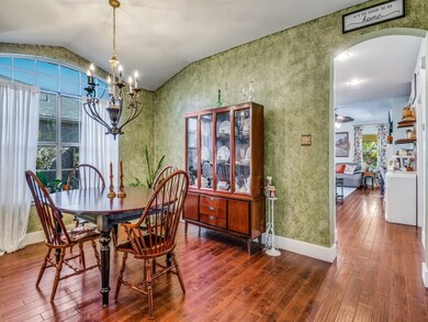 Dining space featuring lofted ceiling, wood finished floors, a chandelier, arched walkways, and wallpapered walls