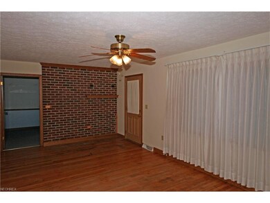 The living room has hardwood flooring and brick ac