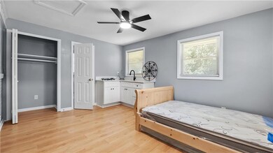 Bedroom featuring attic access, light wood-type flooring, a closet, and ceiling fan