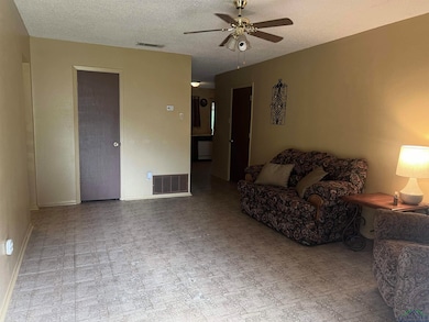 Living room with a ceiling fan, a textured ceiling