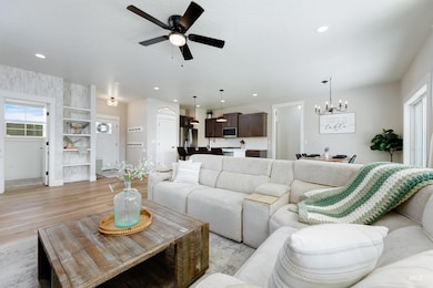 Living room featuring a chandelier, light wood-style flooring, ceiling fan, and recessed lighting