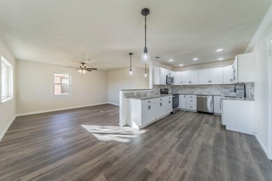 Kitchen with open floor plan, white cabinetry, tasteful backsplash, appliances with stainless steel finishes, and hanging light fixtures
