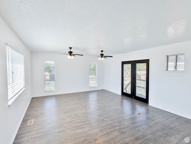 Spare room featuring french doors, dark wood-type flooring, and baseboards