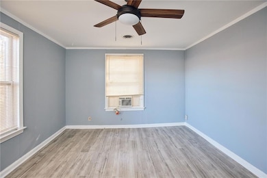 Empty room with a ceiling fan, wood finished floors, crown molding, and cooling unit