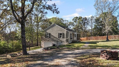 View of property exterior with driveway, an attached garage, and view of wooded area