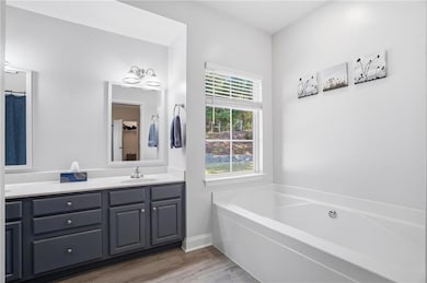 Bathroom with double vanity, a bath, and light wood-style flooring
