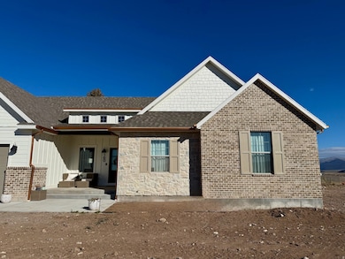 View of front of property featuring a shingled roof, board and batten siding, stone siding, and a patio area