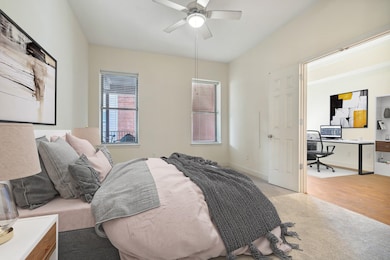 Bedroom with a desk, ceiling fan, light colored carpet, and baseboards