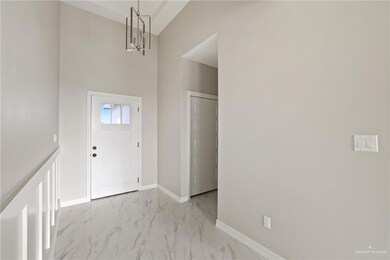 Entryway featuring a chandelier, light marble finish flooring, baseboards, and a high ceiling