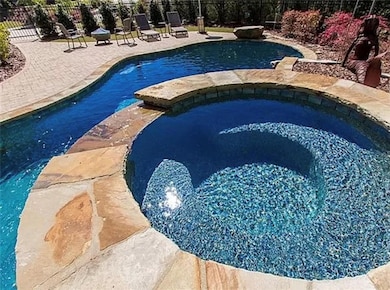 View of pool with a patio area and a pool with connected hot tub