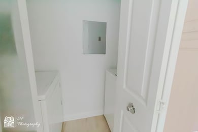 Laundry area featuring electric panel, baseboards,