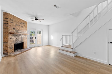 Unfurnished living room with stairs, a fireplace, and light wood finished floors