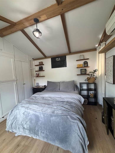 Bedroom featuring a wall mounted air conditioner and wood finished floors