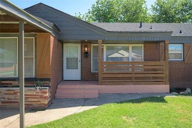 View of front facade featuring brick siding, roof with shingles, and a porch