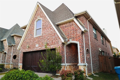 View of front facade featuring brick siding, roof with shingles, and a garage