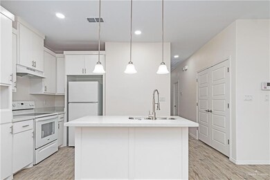 Kitchen with white appliances, sink, a kitchen island with sink, and white cabinets