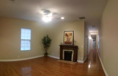Unfurnished living room with wood finished floors, a fireplace with flush hearth, and baseboards