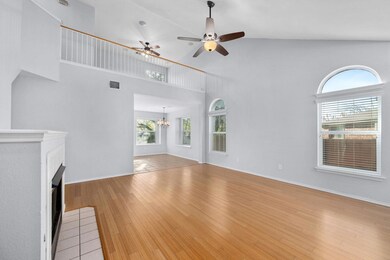 Unfurnished living room with high vaulted ceiling, light wood-style floors, a fireplace with flush hearth, ceiling fan, and a chandelier