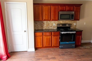 Kitchen featuring appliances with stainless steel finishes, tasteful backsplash, baseboards, and brown cabinets
