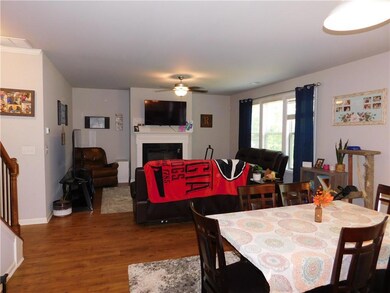 Dining space with wood finished floors, a ceiling fan, a glass covered fireplace, and stairway