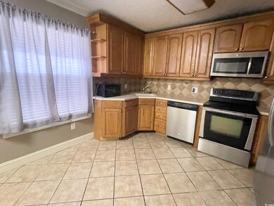 Kitchen featuring appliances with stainless steel finishes, light countertops, tasteful backsplash, light tile patterned floors, and a sink